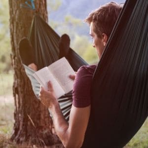 man in hammock reading outside