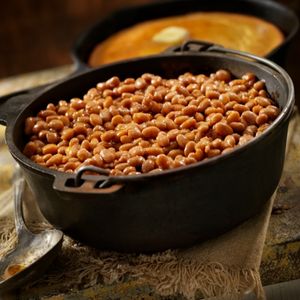 Baked beans cooking in dutch oven for hot dog side dish